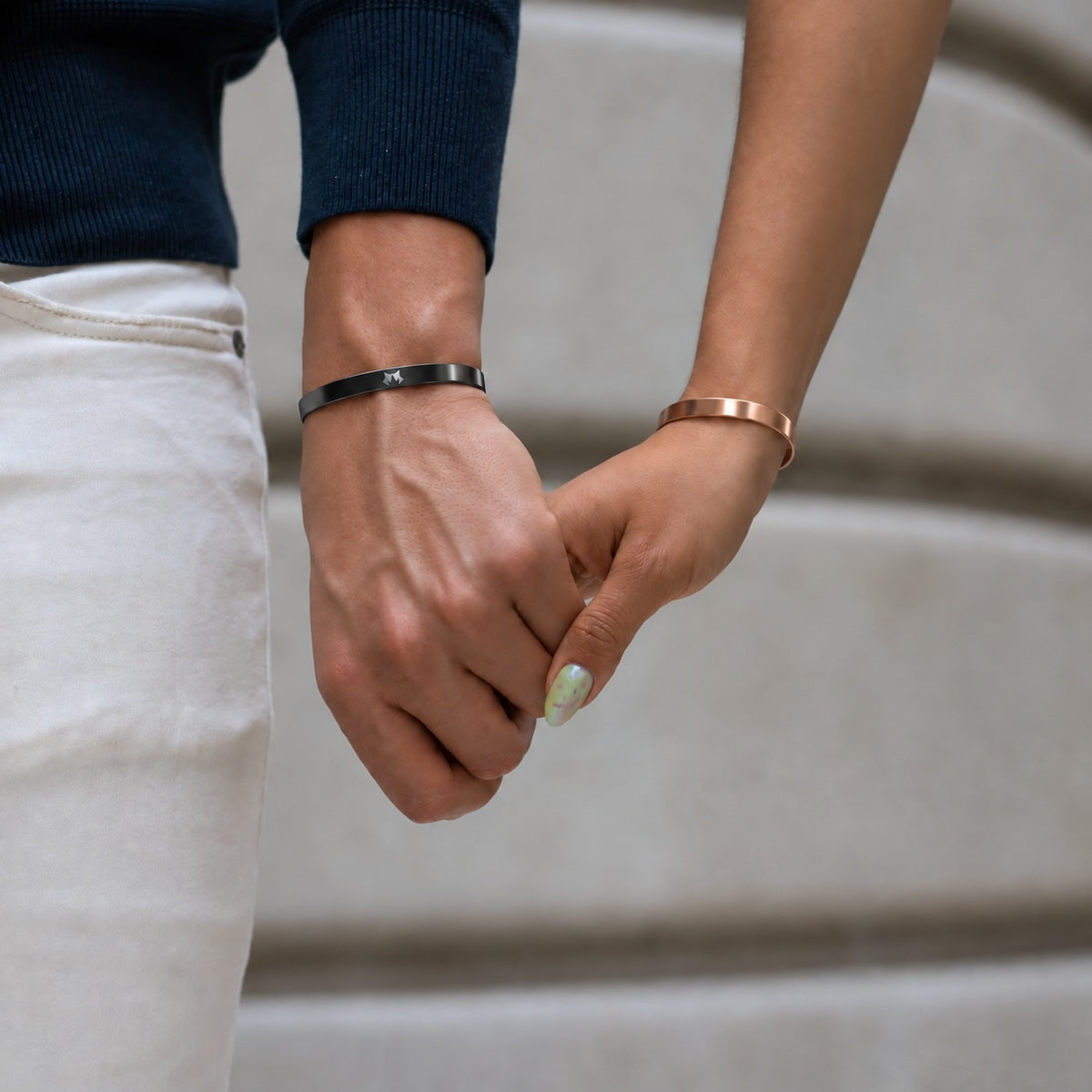 Black and Rose Gold cuffs worn by a couple holding hands