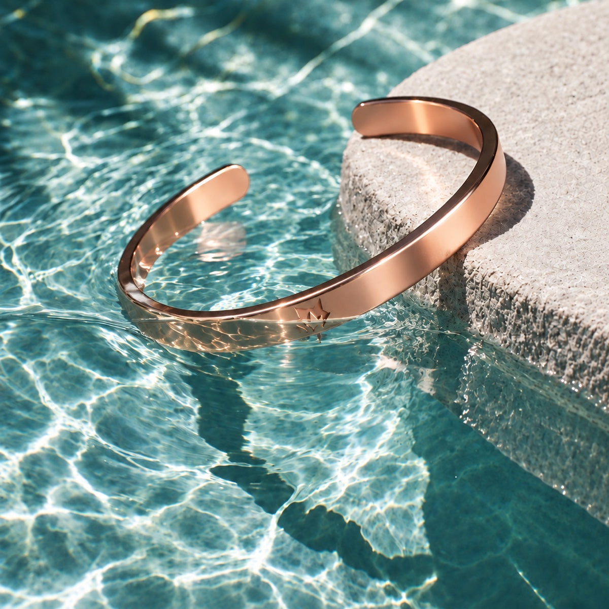 Rose Gold cuff beside turquoise water